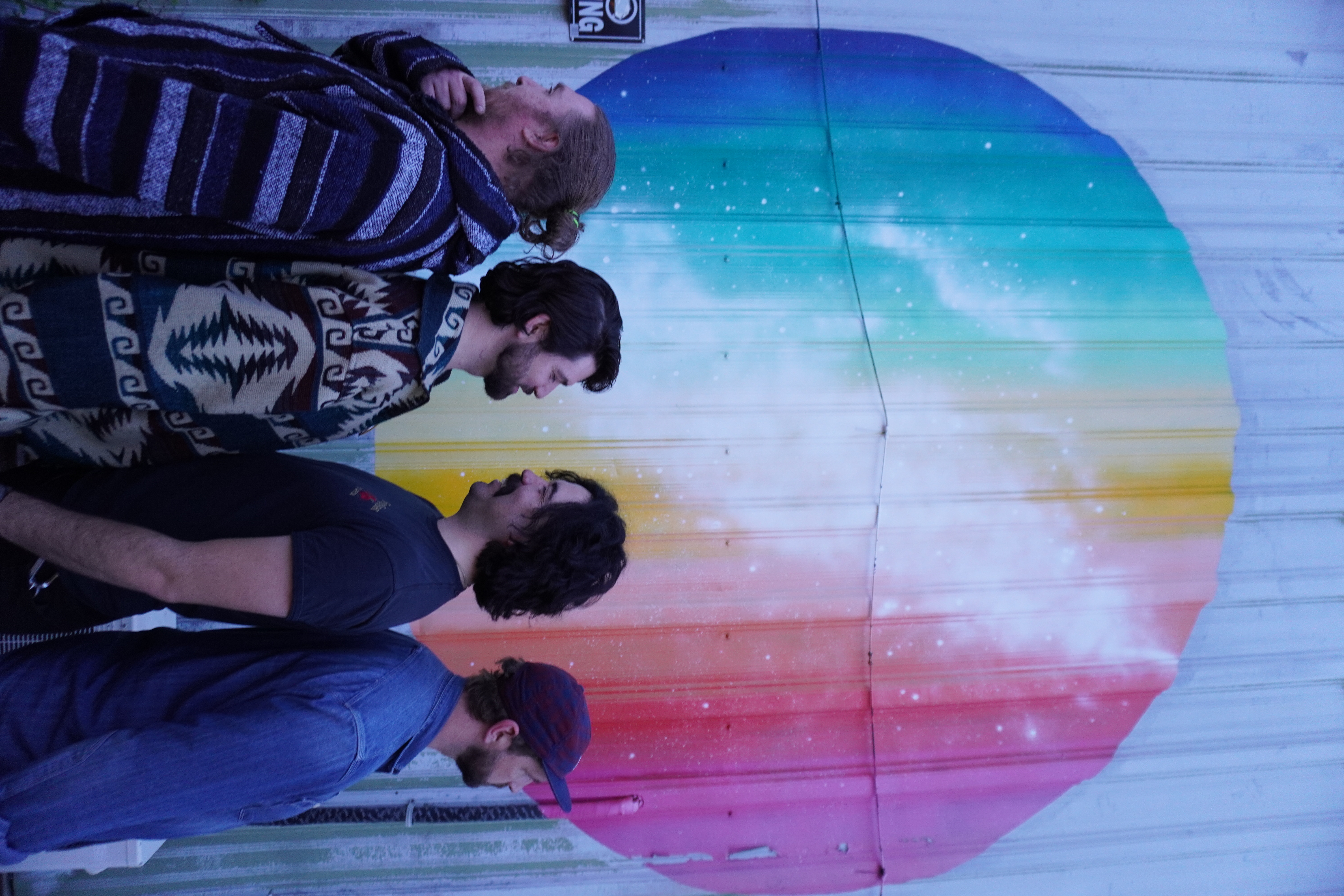 Five Wild Hares back to back in font of some local street art